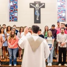 A priest leading a group of students.